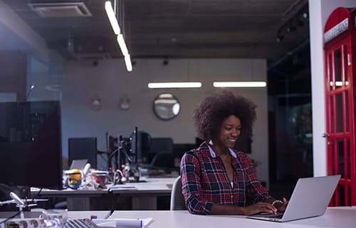 Uma mulher usando um notebook. Cursos na modalidade FLEX.